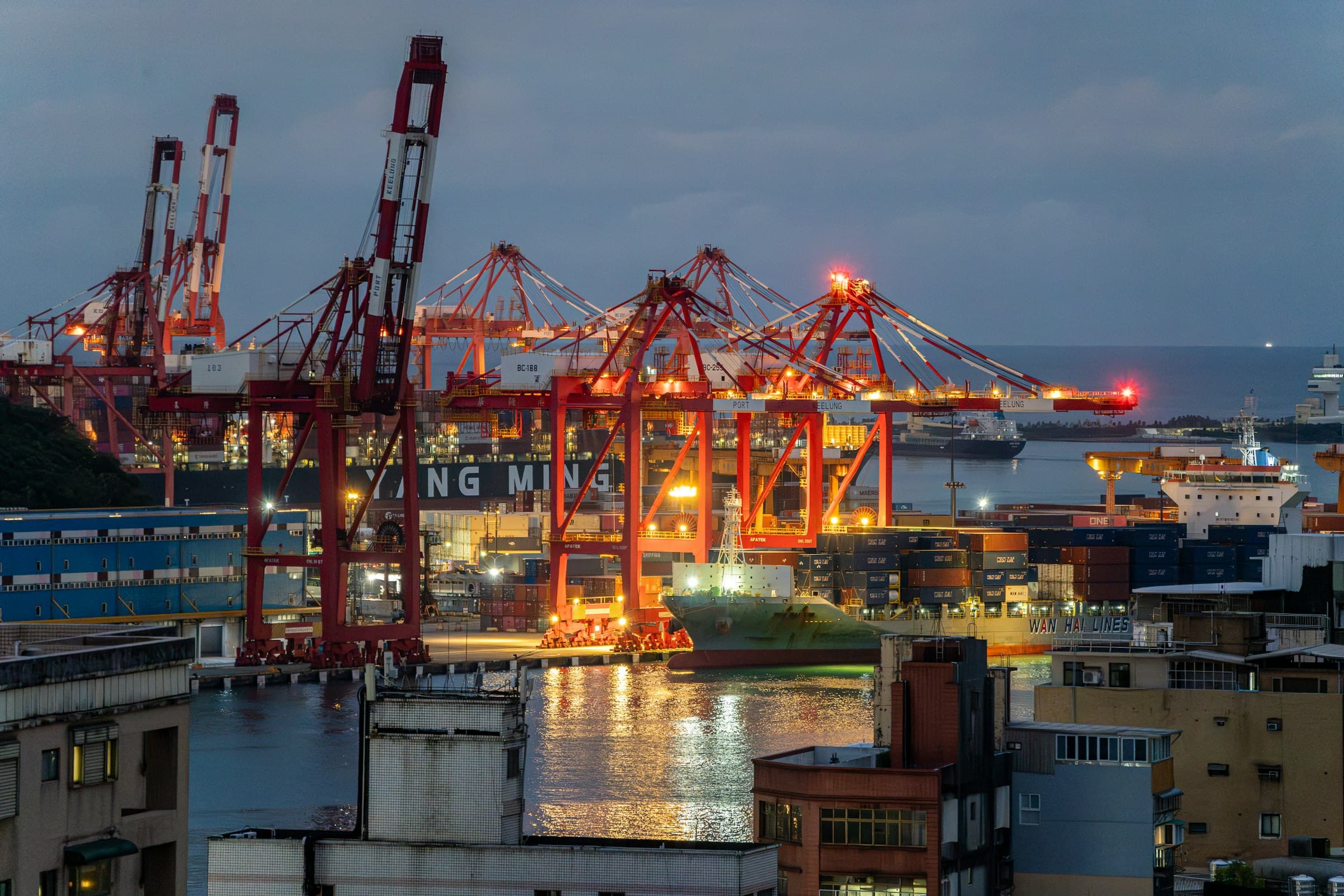 Port cranes and city skyline at dusk