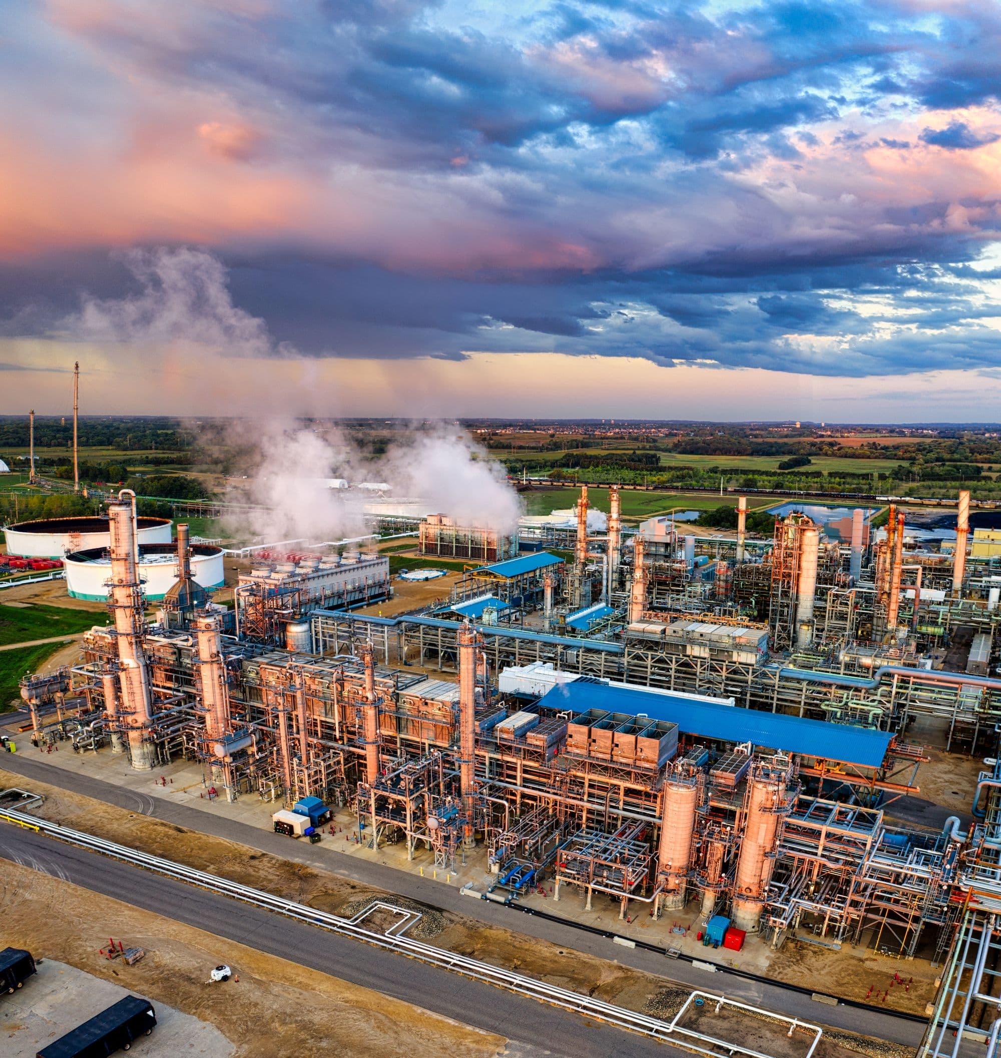 Industrial plant at dusk with steam rising over process units